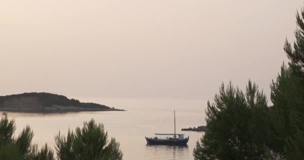 Skymning i en lugn lugn havsvik. Utsikt över träden och ön i fjärran, båten på vattnet. Brett skott, kväll — Stockvideo