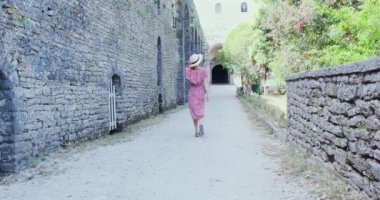 Elbiseli ve şapkalı bir kız, kaleyi geziyor. Taş duvar boyunca avludaki kapıya doğru yürüyor. Arnavutluk ve Cirokaster