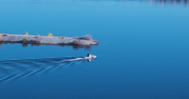 Petit bateau à moteur se déplace le long de la surface parfaitement miroir de l'eau de la rivière à côté du brise-lames en béton, jetée. Vue de dessus, gros plan, ralenti — Video