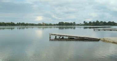 Nehir sahilindeki ahşap iskele. Nehrin yeşil ormana bakan sakin körfezi. Bulutlu hava, gökyüzü, geniş çekim, gündüz.