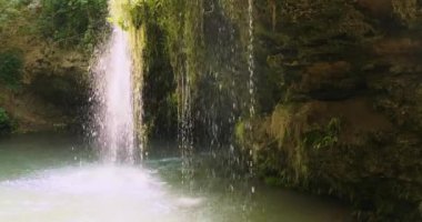 Küçük bir şelale gibi püskürt. Su damlaları yüksek bir yerden göle akar. Yan görüş, gündüz görüntüsü, orta çekim