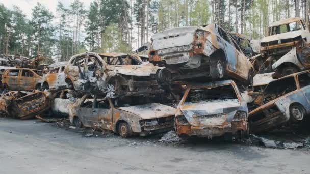Irpin, veel uitgebrande gepantserde auto 's op de parkeerplaats boven elkaar in het midden van het bos, de gevolgen van de invasie van het Russische leger in Oekraïne. Oorlog in Oekraïne — Stockvideo
