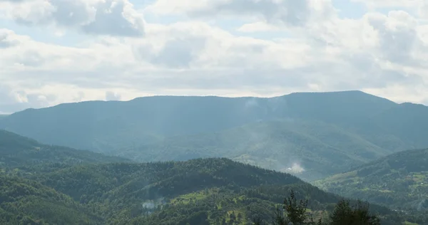 Vista de las montañas con nubes blancas, entre zolmos verdes cubiertos de bosque. La belleza y tranquilidad de la naturaleza. Amplio tiro, durante el día, primavera, verano —  Fotos de Stock