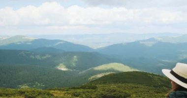 Şapkalı kadın gezgin, yeşil dağlara bakış açısından bakıyor. Yazın Karpatlar 'ın Panorama' sı. Gündüz, orta boy, 4K