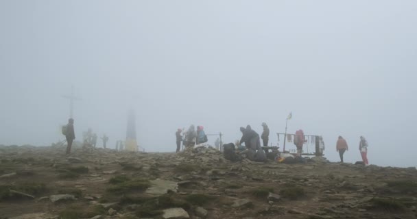 Group of people in the fog on top of Mount Hoverla, Carpathians, Ukraine. Windy weather, gray cloud on top of the mountain, poor visibility. — стокове відео