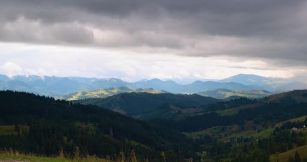 Kilátás a hegyekre, egy nagy szürke felhő lóg az égen, árnyékot teremtve a zöld erdő dombjaira. Tavaszi nyár a Kárpátokban, Ukrajna. — Stock videók