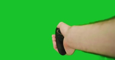 Bir adamın eli akıllı bir TV 'nin uzaktan kumandasını tutuyor ve üzerine tıklıyor, açıp kapatıyor, krom anahtarın menüsünü ayarlıyor. Yeşil ekran, yakın çekim, birinci şahıs görüntüsü, pov. Yüksek kalite 4k görüntü