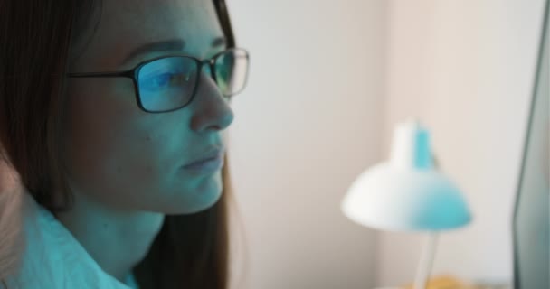 一个戴眼镜看着监视器的女人的脸 屏幕在眼镜中的反射 疲倦的眼睛 在电脑上的工作 显示器上的保护眼镜 专注地寻找 高质量的4K镜头 — 图库视频影像