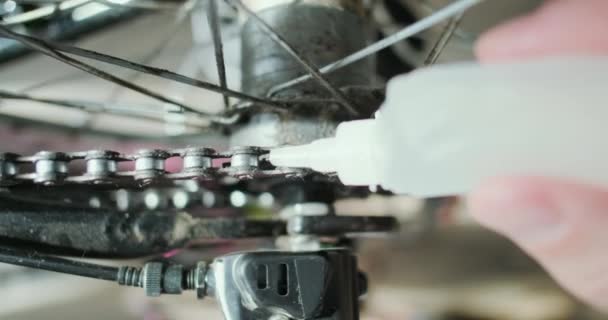 用瓶装油润滑自行车链条的连接线 一只手握着管子 在转动后轮时把润滑油滴在链条上 高质量的4K镜头 — 图库视频影像