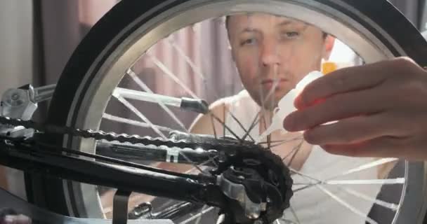 정비공 바퀴에 뒤집힌 자전거 체인에 윤활유를 뿌리고 클로즈업 바퀴는 태양은 — 비디오