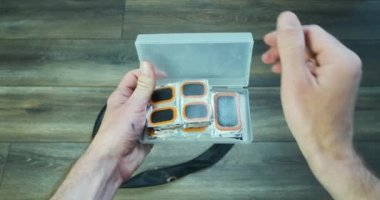 Erkek eller, bisiklet iç tüplerini tamir etmek için plastik bir kutu açar. Arka planda kırık bir kamera var. Bakış açısı. Yüksek kalite 4k görüntü