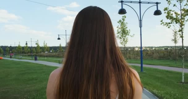 Een Langharige Bruinharige Vrouw Loopt Langs Een Trottoir Een Park — Stockvideo