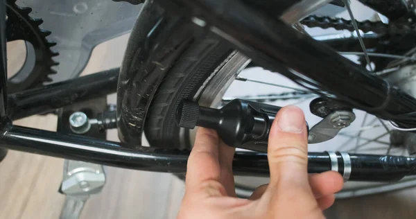 Man hand turns off the bicycle dynamo. Removes dynamo from bike tire. Close-up, indoors. High quality 4k footag