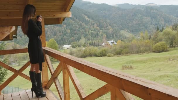 Femme Élégante Bottes Manteau Noir Tient Sur Balcon Bois Terrasse — Video