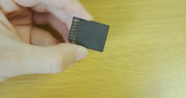 SD memory card. Yellow contacts shimmer in the light. The hand holds a memory card for the camera. High quality 4k footage