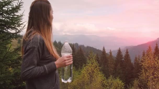 Молодая Девушка Пьет Воду Бутылки Зеленом Лесу Смотрит Закат Горах — стоковое видео