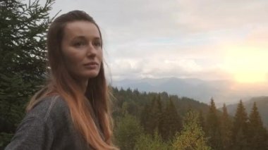 Güzel bir kadın dağlardaki parlak güneşe bakar. Yeşil orman, portre, yakın plan. Doğanın güzelliği, sağlık, hayatın keyfi kavramı. Yüksek kalite 4k görüntü