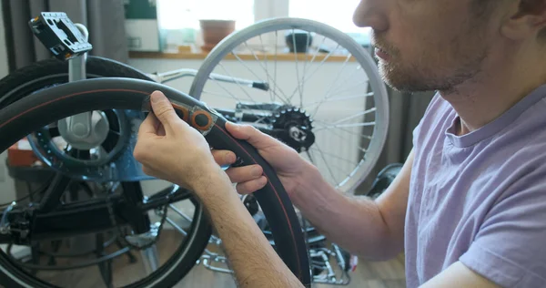 man inspects bicycle inner tube for punctures. Trying on a tire. Looks at the sealed patches. The concept of a home bike workshop, do it yourself, repair it. Close-up, indoors. High quality 4k footage