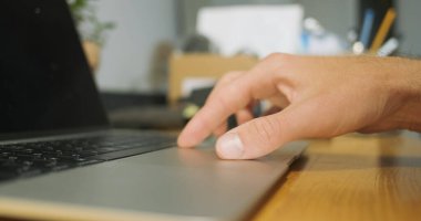 Mans touchpad laptop, yakın çekim, yan görüş, yüzey üzerinde parmak kaydırma. Bilgisayarla, masaüstüyle çalışıyorum. Bilgisayar teknolojisi konsepti, uzaktan çalışma, evde çalışma, internette sörf.