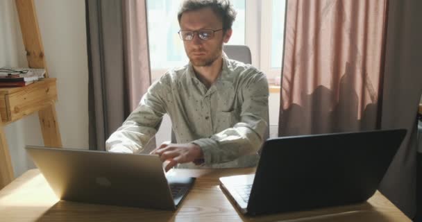 Young Man Working Two Laptops Desktop Prints One Second Computer — стоковое видео