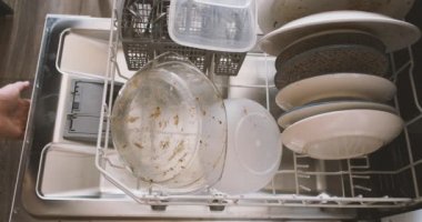 İnsanlar bulaşık makinesine kirli bulaşık dolu tepsileri doldurur ve kapağı kapatır. Üst manzara, yakın plan. Ev ödevi, bulaşık yıkama, ev hayatı. Yüksek kalite 4k görüntü