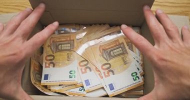 Erkek eller, içi avro nakitiyle dolu karton kutuyu açar. Üst manzara, yakın plan. Gizli para, miras, hediye, gölge ekonomi kavramı. Yüksek kalite 4k görüntü