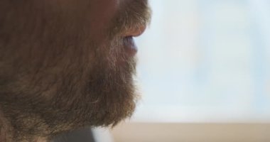 Man drinks morning coffee from black cup. Side view, close-up, face, beard, unrecognizable silhouette. Concept of a morning drink, wake up, think, recover, prepare for work. High quality 4k footage