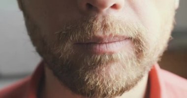 Tıraşsız adam çenesini oynatıyor, yemek çiğniyor. Yakın çekim, tanınmayan yüz, ön manzara. Yemek yeme konsepti, oburluk, lezzetli yemekler, atıştırmalık, kahvaltı, öğle yemeği, akşam yemeği. Yüksek kalite 4k