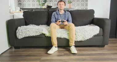 Man plays on the console while sitting on the couch. Leggy girl distracts from the game, passing by the screen. The concept of passion for video games, relationships, seduction. High quality 4k