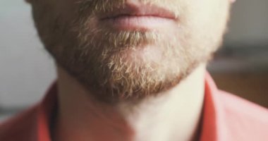 Man approaches the camera and strokes his beard. Blurred background, close-up. The concept of thoughtfulness, reflection, thinking about, male beauty. Concept of ponder, meditate, philosophize. High