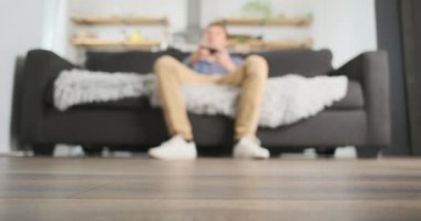 Male player blur plays the console while sitting on the couch. Front view. Girlfriends legs are stand in front of the screen, making it difficult to play. Concept of gambling, attracting attention