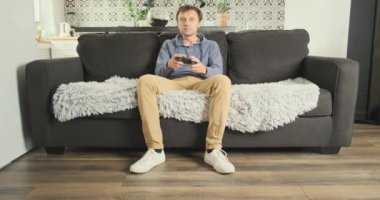 Male player blur plays the console while sitting on the couch. Front view. Girlfriends legs are stand in front of the screen, making it difficult to play. Concept of gambling, attracting attention