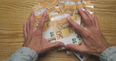 Hands collect many scattered 50 euro banknotes. Clear cash money off the table. High quality 4k footage