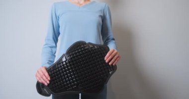 Woman holds in her hands a motorcycle back protection for a jacket. Hands crumpling a plastic shield. Front view, demonstration of a motorcycle accessory for protection. High quality 4k footage