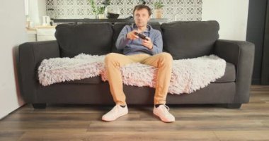 Man plays on console in living room. Beautiful wife interferes with playing, comes and takes the gamepad. Concept of gambling, attracting attention, relationships. High quality 4k footage