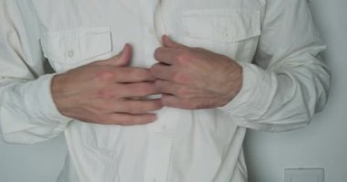 Man opens a white shirt to show off a skin condition called pityriasis versicolor. Hand scratches red spots on the skin. Medicine, dermatology. High quality 4k footage