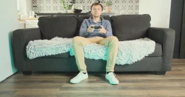 Wife prevents her husband from playing on console. Fits and covers the screen. Young man is playing on console while sitting on couch. Concept of gambling, attracting attention, relationships. High