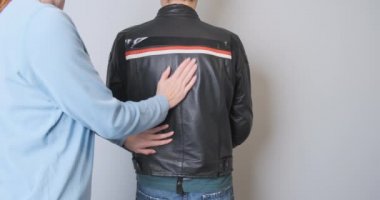 Woman pulls out a back protector from a motorcycle jacket worn by a man. Attaches plastic to the back, view from the back. Demonstration of a plastic shield. High quality 4k footage