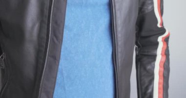 Man zips up a black leather jacket. Close-up, chest, front view. High quality 4k footage