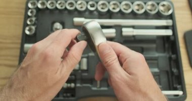 Man connects the adapter to the socket wrench. Pov, on the background of a set of tools with bits and socket heads. Top view, close-up. High quality 4k footage