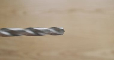 Rotating drill, close-up, on the background of a wooden tabletop. Demonstration of the operation of an electric screwdriver with a drill for metal. High quality 4k footage