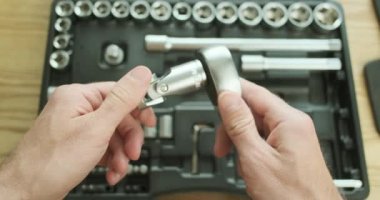 Mans hand disconnects an adapter to a ratchet wrench, against the background of an open set of tools lying on the table. High quality 4k footage