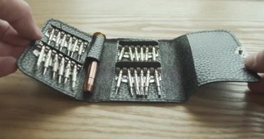 male hands close a set of mini screwdrivers with bits lying on the table in a leather case. The concept of finishing work. First-person view. High quality 4k footage