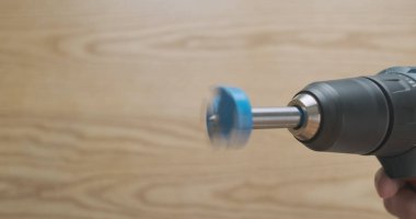 forstner drill rotating in an electric screwdriver. Demonstration of work, close-up, side view on the background of a wooden tabletop. High quality photo