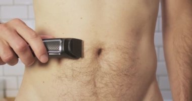 Young man shaves his belly with a trimmer. Front view, close-up, hair removal. Metrosexual, male beauty, personal care. High quality 4k footage