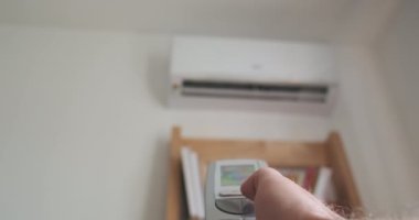 Mans hand turns off the air conditioner using a remote control. Close-up, blurred air conditioner hanging on the wall. High quality 4k footage