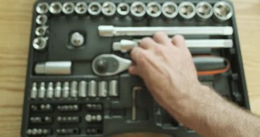 Auto mechanic connects an adapter to a ratchet wrench and demonstrates how it works. A set of tool bits and heads lying on the table. Top view, close-up, first-person view. High quality 4k footage