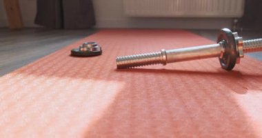 Krepsiz metal halter yerdeki parlak yoga minderinin üzerinde yatıyor. Sporu bırakma konsepti, tembellik, motivasyondaki zorluklar. Yüksek kalite 4k görüntü