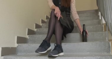 Genç bir kadın bir apartmanın beton merdivenlerinde oturur ve şişeden bira içer. Partiden sonra tanınmayan üzgün bir kız, şirket partisi, elbise ve spor ayakkabılar içinde. Ön görüş, alkolizm