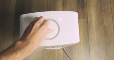 Beyaz buhar çıkışının yönünü değiştiriyorum. Hava nemlendirici, üst manzara. Adam hortumu çevirip çıkış yönünü değiştiriyor. Üst manzara, birinci şahıs görünümü. Yüksek kalite 4k görüntü